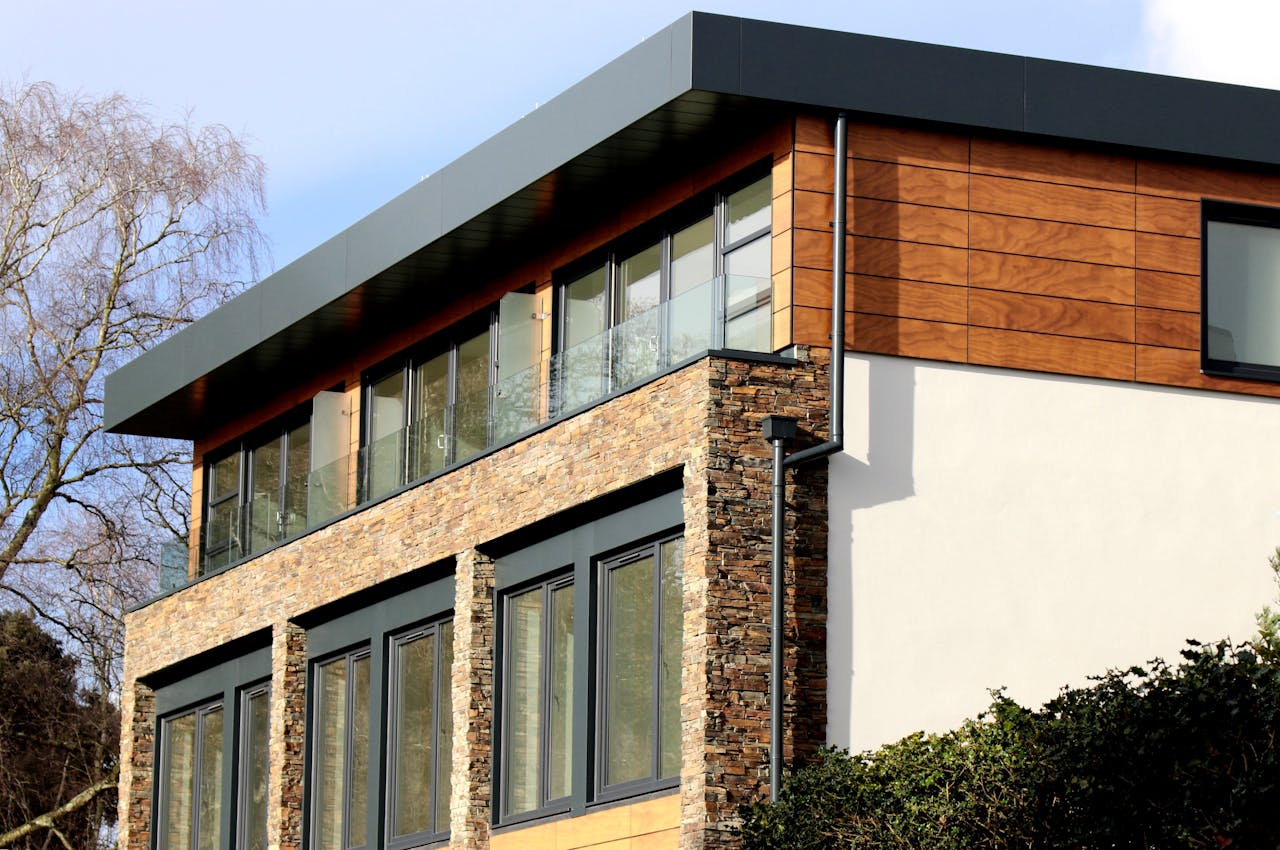 Contemporary house in Poole featuring a striking mix of stone and wood facade with large windows.